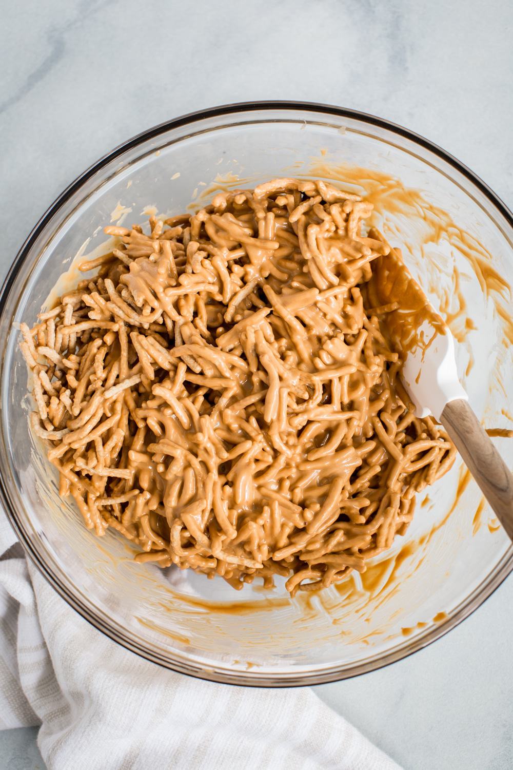 Fideos chow mein en la mezcla de caramelo en un cuenco de cristal.